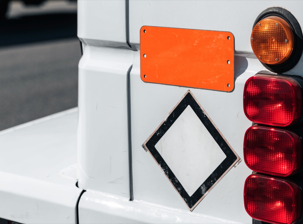Orange ADR-Warntafel und rautenförmiger Gefahrzettel an einem Transportfahrzeug