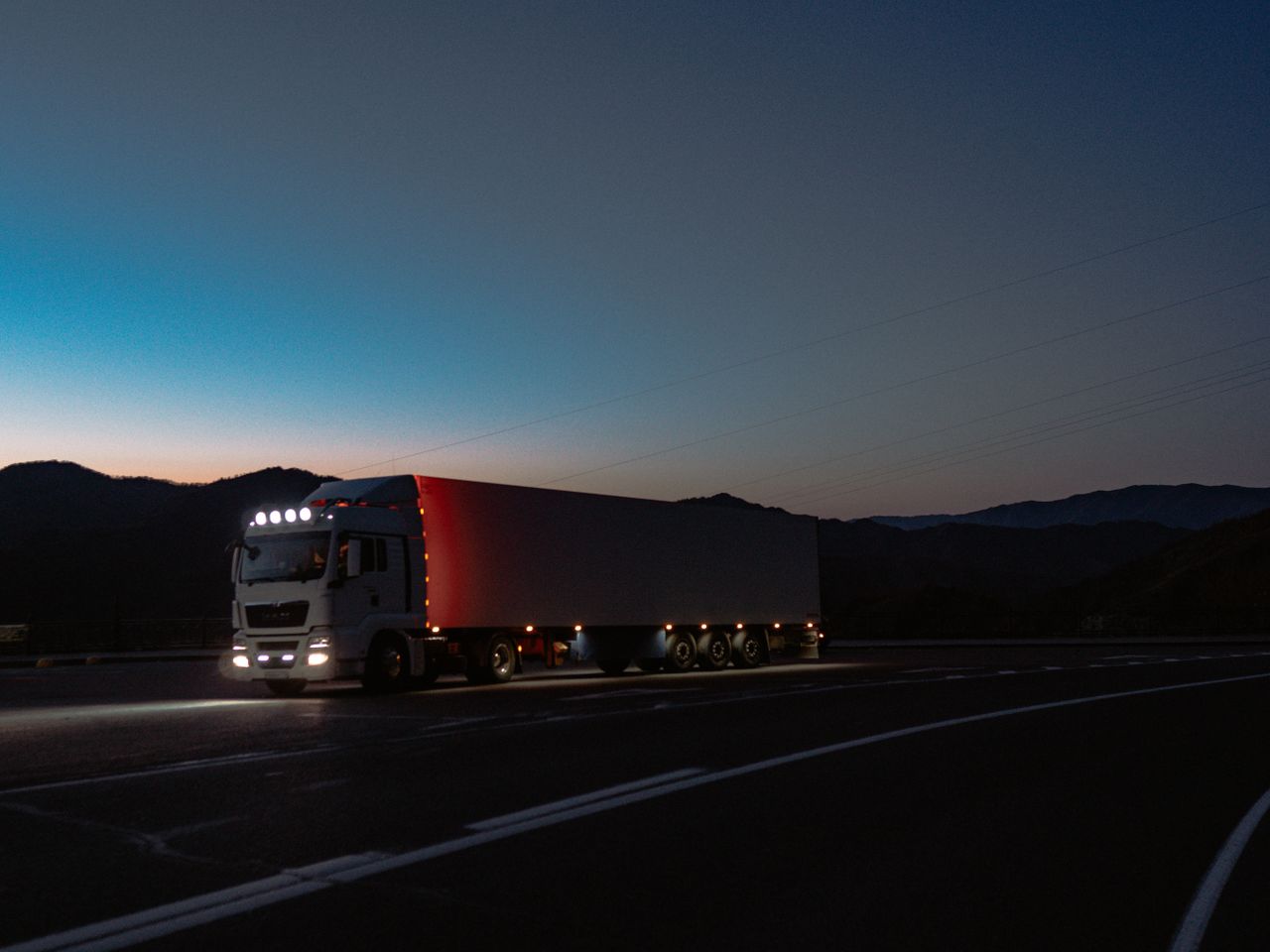 Lkw in der Abenddämmerung unterwegs: Overnight-Direktfahrt für die Zustellung am Morgen