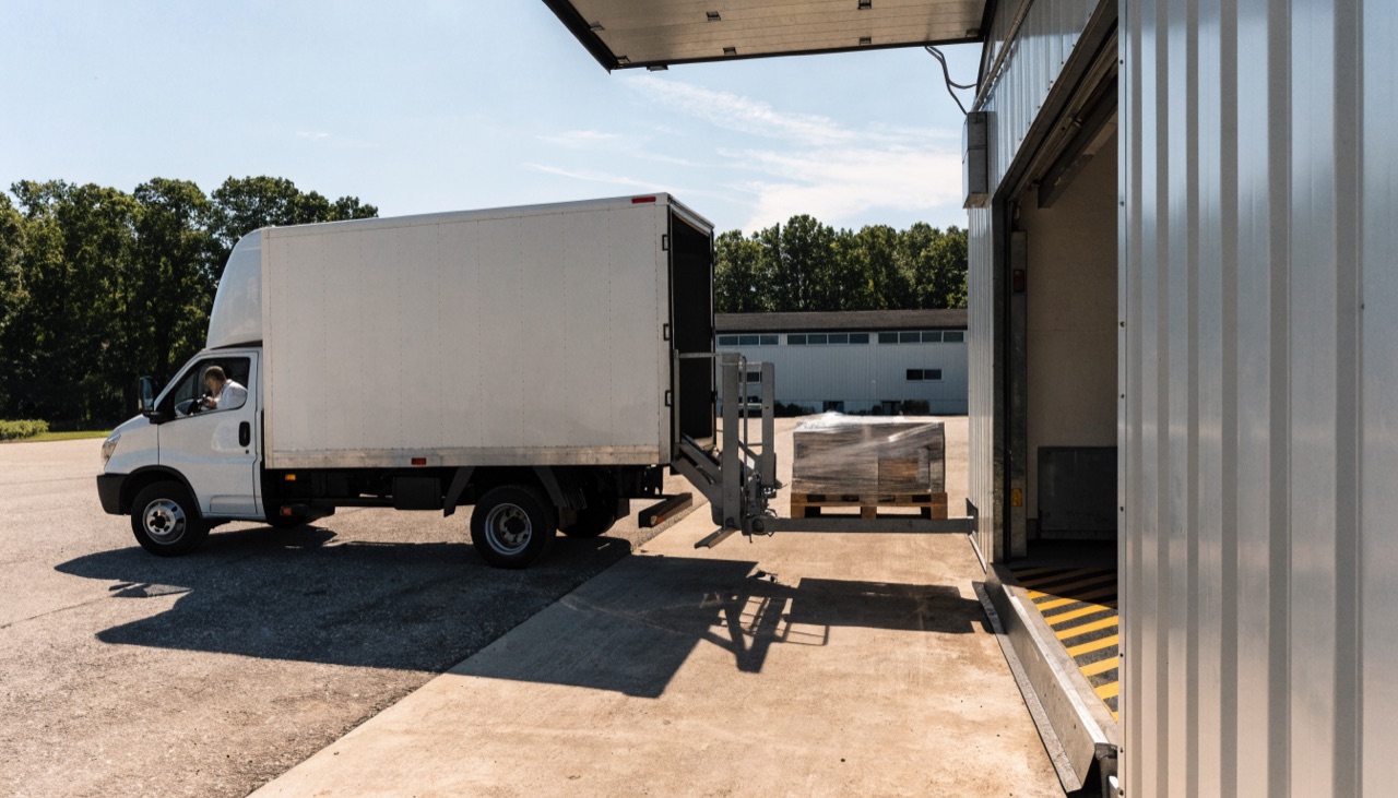 Lkw mit hydraulischer Ladebordwand senkt eine Palette auf Bodenhöhe ab